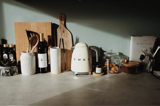 Plan de cuisine minimaliste avec des ustensiles, des bouteilles d'huile, un bouilloire SMEG et des bocaux en verre.