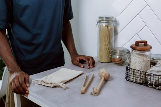 Un homme debout près d'une table avec des ustensiles en bois, des bocaux en verre et un sac en tissu pour une cuisine zéro dé